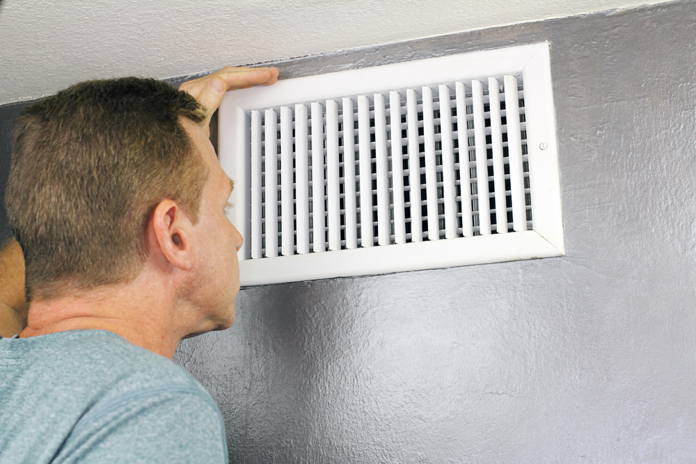 man inspecting air duct to see if it needs cleaning