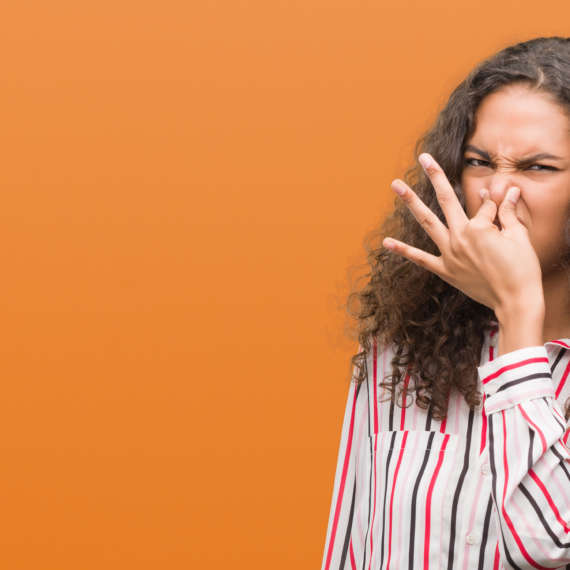 Woman holding nose from something that smells bad
