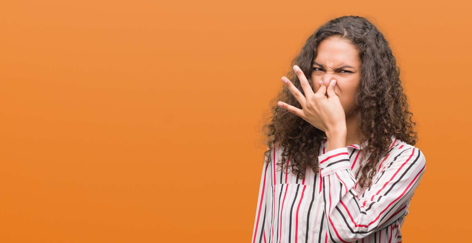 Woman holding nose from something that smells bad